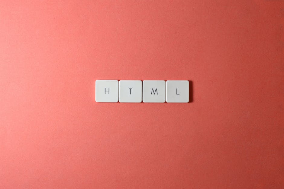 A close-up image of four white square tiles with black letters spelling 'HTML' arranged in a horizontal line on a smooth, coral-colored surface. The tiles are evenly spaced and aligned, with the backg